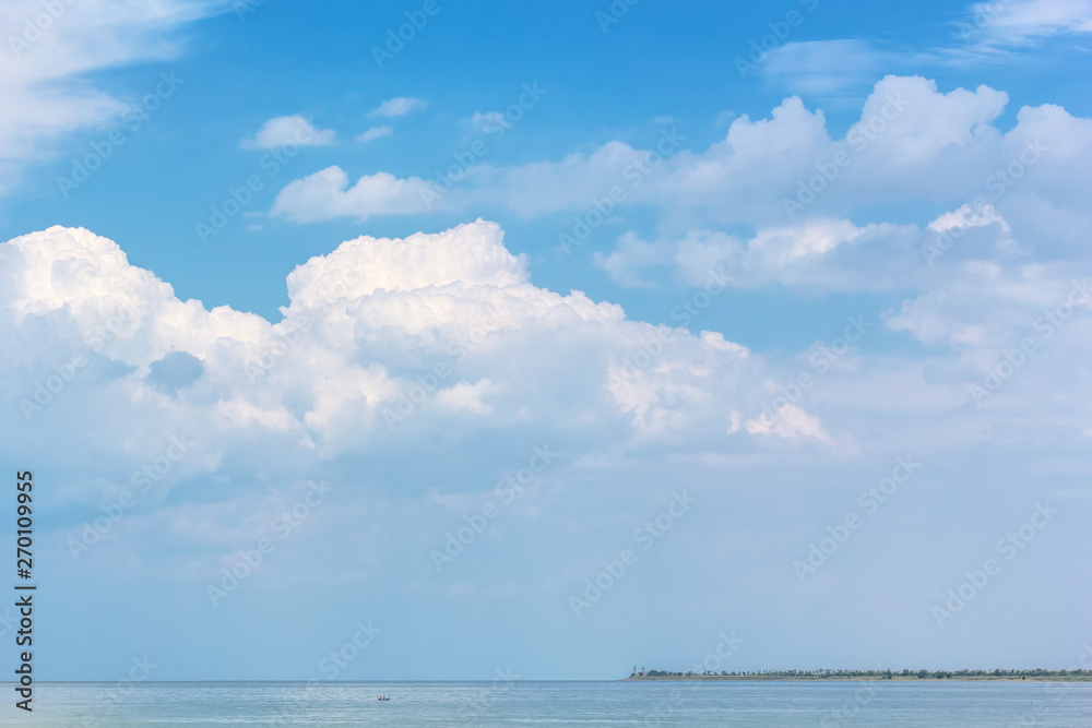 Obraz premium Picturesque seascape with white clouds above the sea