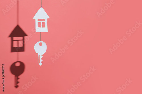 small house and key made of cardboard casts a shadow on a bright colored background