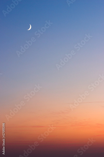 Beautiful summer sunset - dark blue sky with visible moon and orange horizon