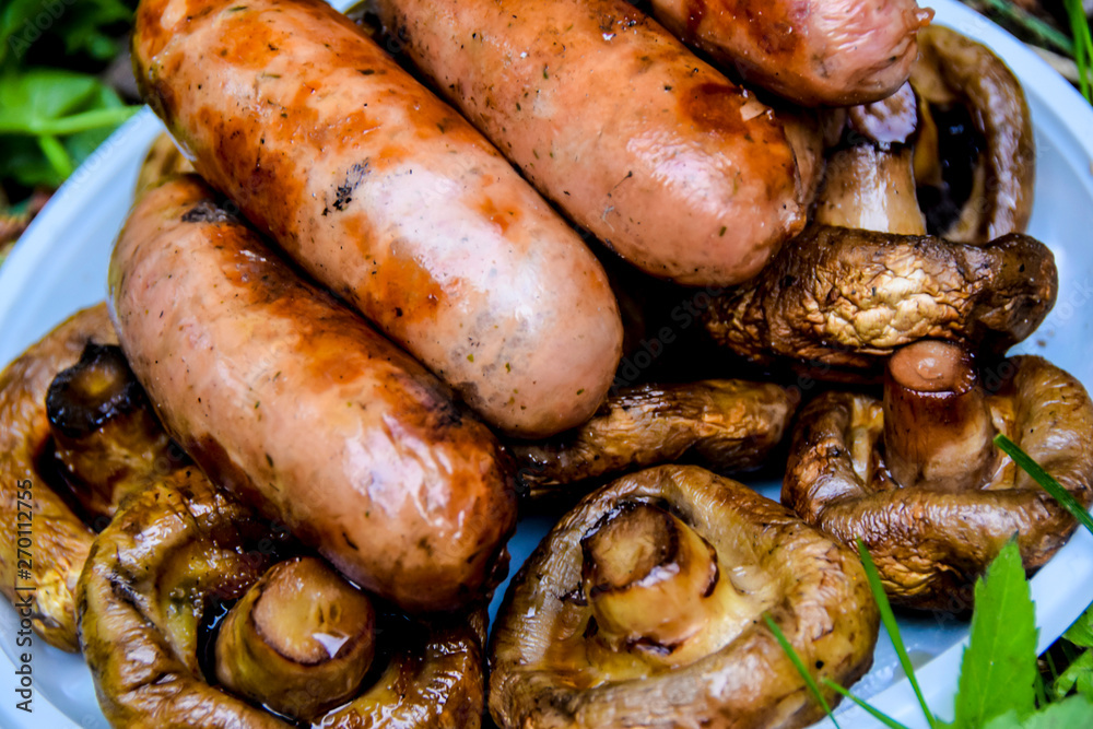 barbecue on the nature in summer mushrooms meat sausages kebab grill lies on a plate on the grass barbecue on the nature in summer mushrooms meat sausages kebab grill lies on a plate on the grass