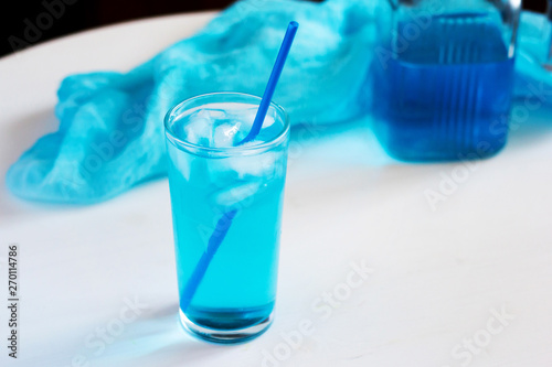 Glass with a blue cocktail with ice on a white background.