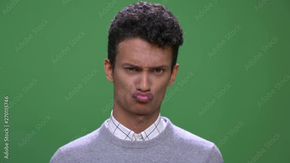 Closeup shoot of young attractive indian male making funny facial expressions looking at camera with background isolated on green Closeup shoot of young attractive indian male making funny facial expressions looking at camera with background isolated on green