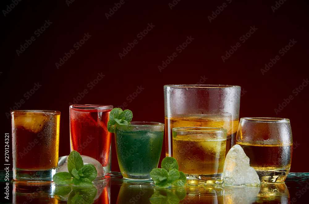 Set of alcoholic cocktails with ice and mint on a red background Set of alcoholic cocktails with ice and mint on a red background