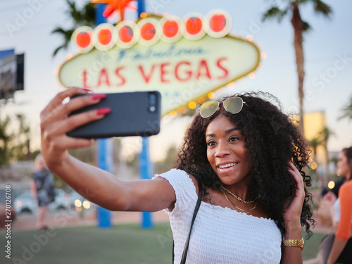 Photography african american woman taking selfie with smartphone in front of welcome to las