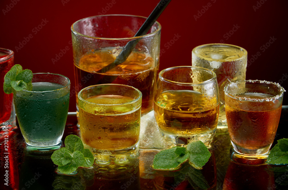 Colored alcoholic drinks with ice and mint on red background Colored alcoholic drinks with ice and mint on red background