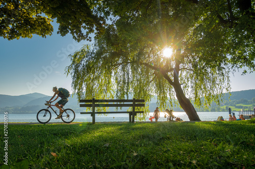 Woman is riding a bike in front of a lake in summer. photo