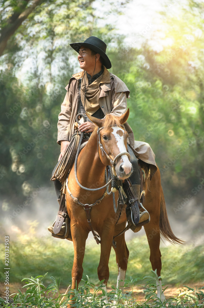 cowboy with his purebred horse standing in the forest cowboy with his purebred horse standing in the forest