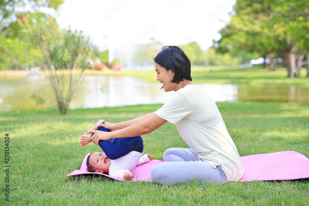 Portrait of Asian mother doing baby yoga for her son on green lawn in the nature garden outdoor. Portrait of Asian mother doing baby yoga for her son on green lawn in the nature garden outdoor.