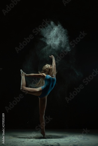 Fototapeta Naklejka Na Ścianę i Meble -  Graceful blonde dancing in dust cloud profile view