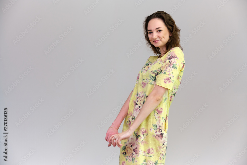 Life is a success. I am pleased with myself. Concept photo of a happy smiling woman satisfied life contented brunette girl in a yellow dress on a gray background with flowing hair. Life is a success. I am pleased with myself. Concept photo of a happy smiling woman satisfied life contented brunette girl in a yellow dress on a gray background with flowing hair.