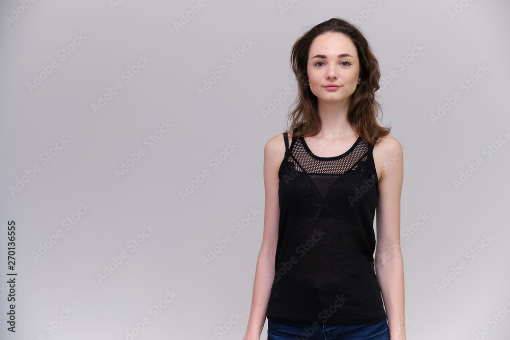 Life is a success. I am pleased with myself. Concept photo of a happy smiling woman satisfied life contented brunette girl in a black T-shirt and jeans on a gray background with flowing hair. Life is a success. I am pleased with myself. Concept photo of a happy smiling woman satisfied life contented brunette girl in a black T-shirt and jeans on a gray background with flowing hair.