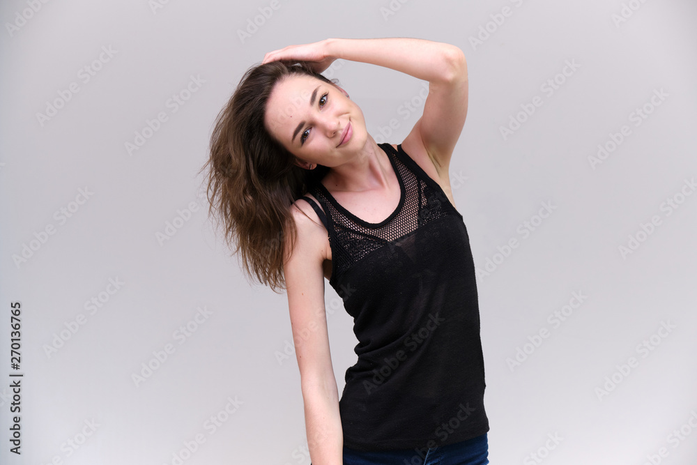 Life is a success. I am pleased with myself. Concept photo of a happy smiling woman satisfied life contented brunette girl in a black T-shirt and jeans on a gray background with flowing hair. Life is a success. I am pleased with myself. Concept photo of a happy smiling woman satisfied life contented brunette girl in a black T-shirt and jeans on a gray background with flowing hair.