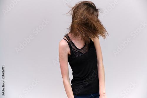 Life is a success. I am pleased with myself. Concept photo of a happy smiling woman satisfied life contented brunette girl in a black T-shirt and jeans on a gray background with flowing hair.