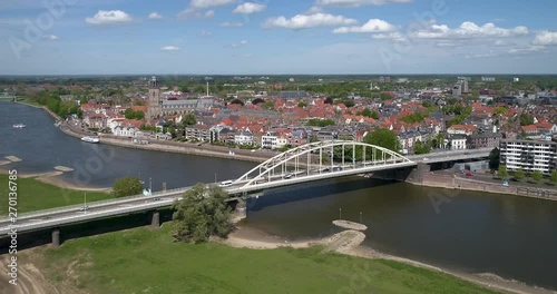 4k Aerial drone shot flying along the Wilhelmina bridge above the river the IJssel showing the sunny skyline of the old Dutch Hanza city Deventer and its landmark church tower of the Lebuinus kerk. photo