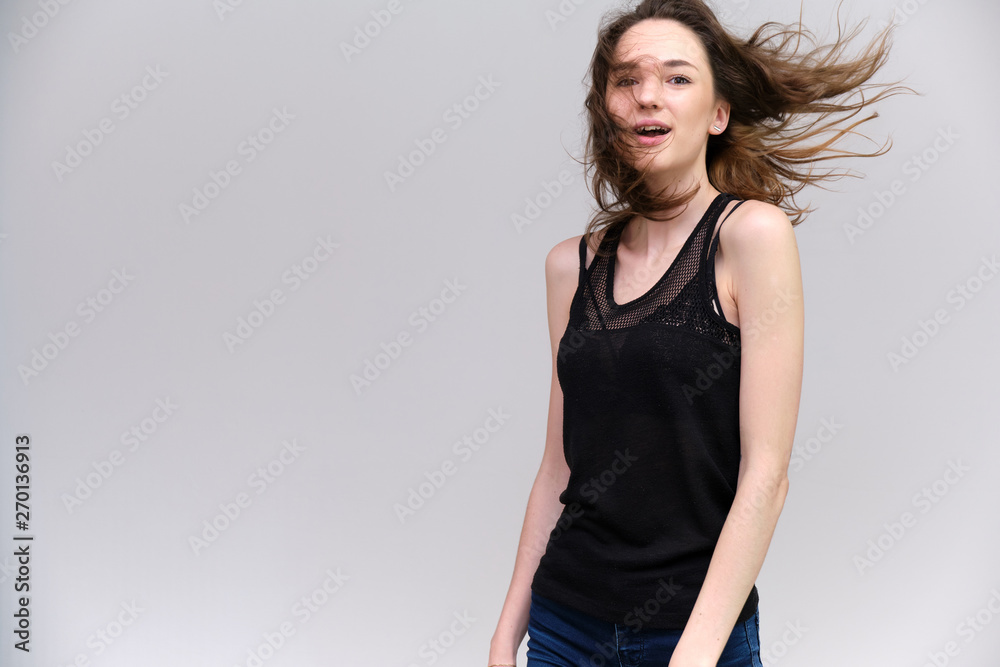 Life is a success. I am pleased with myself. Concept photo of a happy smiling woman satisfied life contented brunette girl in a black T-shirt and jeans on a gray background with flowing hair. Life is a success. I am pleased with myself. Concept photo of a happy smiling woman satisfied life contented brunette girl in a black T-shirt and jeans on a gray background with flowing hair.