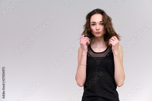 Life is a success. I am pleased with myself. Concept photo of a happy smiling woman satisfied life contented brunette girl in a black T-shirt and jeans on a gray background with flowing hair. © Вячеслав Чичаев