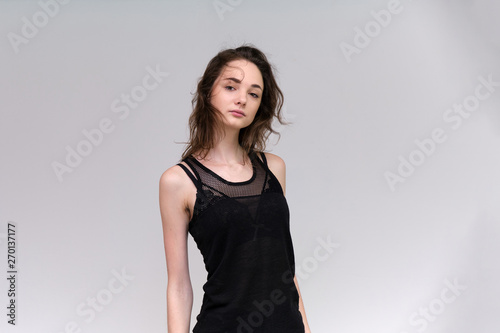 Life is a success. I am pleased with myself. Concept photo of a happy smiling woman satisfied life contented brunette girl in a black T-shirt and jeans on a gray background with flowing hair.