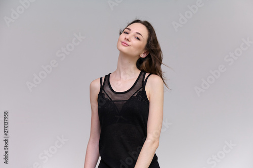 Life is a success. I am pleased with myself. Concept photo of a happy smiling woman satisfied life contented brunette girl in a black T-shirt and jeans on a gray background with flowing hair.