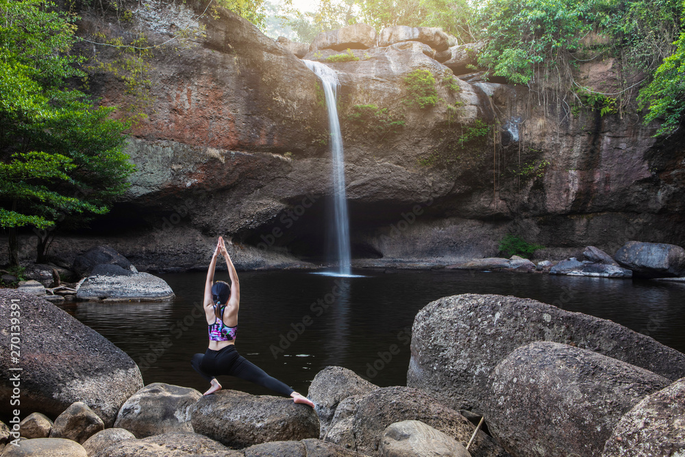 Young girl asian women is playing  yoga in front of the waterfall.