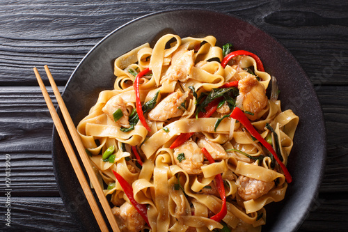 Obraz na plátne Drunken noodles pad kee mao with chicken, basil, chili pepper and sauce close-up on a plate