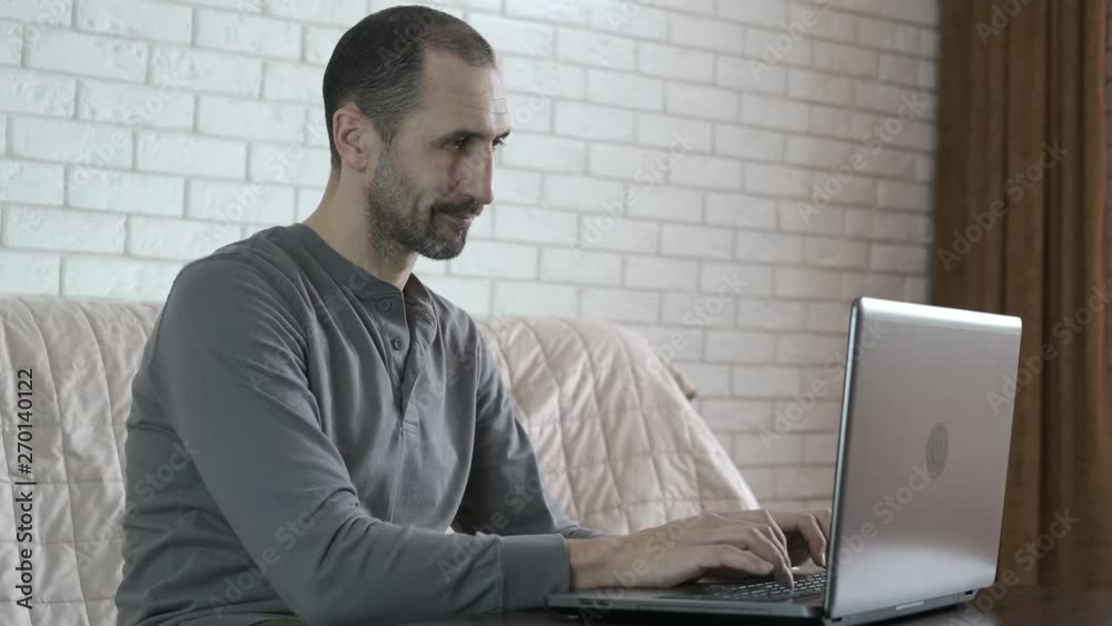 A man works at home at the computer. Freelancer at home using a laptop. A man works at home at the computer. Freelancer at home using a laptop.