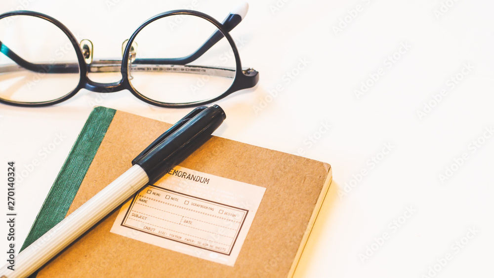 Brown craft paper cover notebook with pen and eyeglasses on desk isolated white background. Brown craft paper cover notebook with pen and eyeglasses on desk isolated white background.