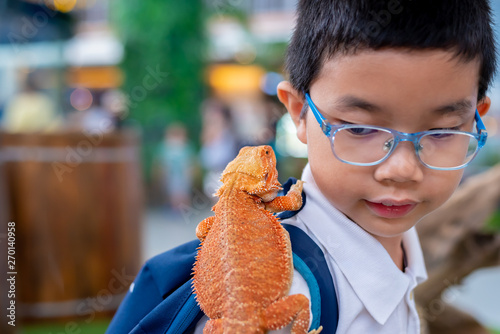 boy hold Bearded Dragon on shoulder.