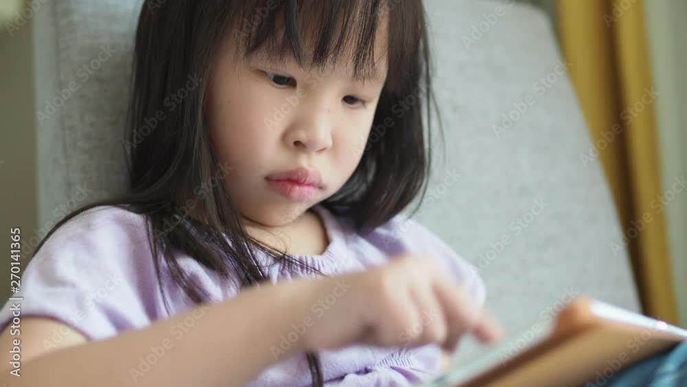 Little asian girl playing games on tablet computer Little asian girl playing games on tablet computer