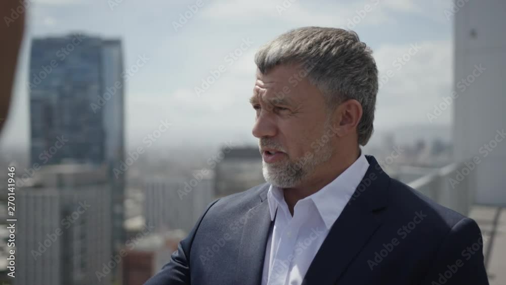 Two businessmen discuss project's details on a rooftop. Process of making good business deal. Two businessmen discuss project's details on a rooftop. Process of making good business deal.