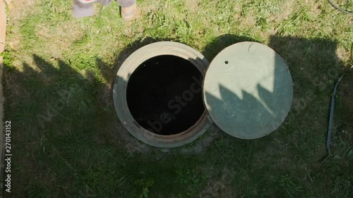 female plumber departs from open draining manhole after an inspection. top view. Maintenance cesspool.