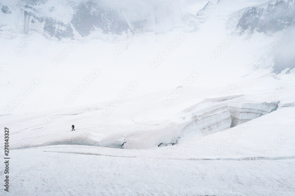 Tourist walking on the glacier near the crack. View to the Mensu glacier. Belukha Mountain area. Altai, Russia.