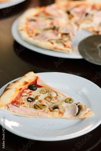 Mushroom pizza slice on white ceramic plate over the table.