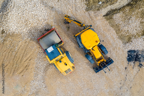 stunning aerial view of the stopped yellow excavator and drum roller at a construction site