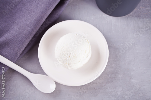 Ice cream on a white ceramic plate with gray napkin and gray mug on a gray table