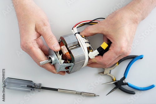 Old elderly home craftsman repairs the electric motor from mincer
