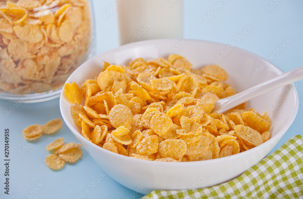 A bowl of dry corn flakes cereal on blue background A bowl of dry corn flakes cereal on blue background