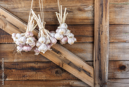 Bundles of fresh garlic dried on vintage wooden wall photo