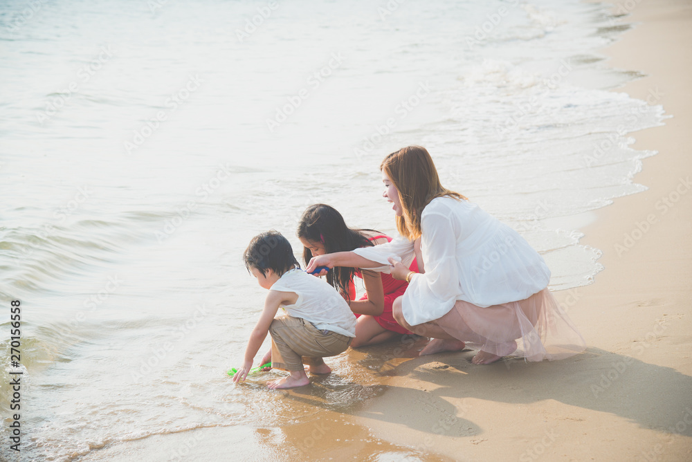 Asian single mom playing with her children on the beach