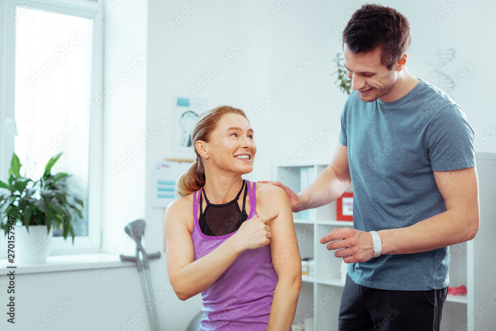 Fototapeta premium Joyful positive blonde woman pointing at her shoulder