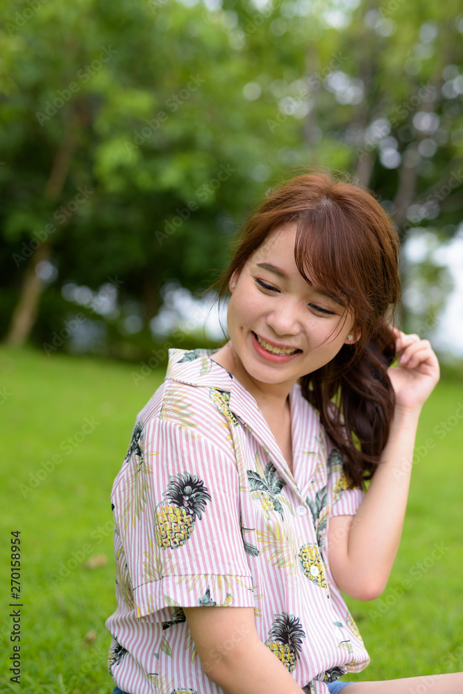 Young beautiful Asian tourist woman relaxing at the park