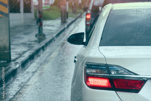 Backside of white car open light break on the road in the time of rain. Cars and wet asphalt roads.