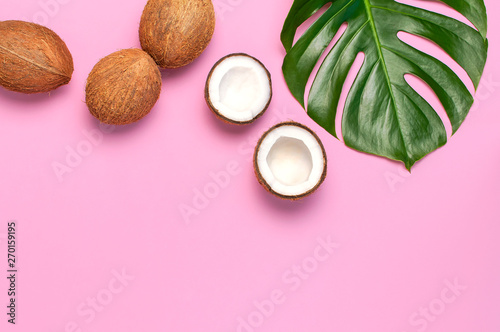Tropical leaves and fresh coconut on pink background. Flat lay  top view  copy space. Summer background  nature. Healthy cooking. Creative healthy food concept  half of coconut