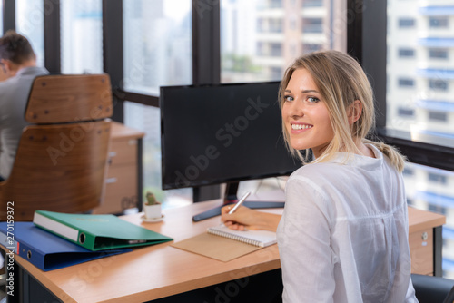Young smiling business woman computer in office, copy space.