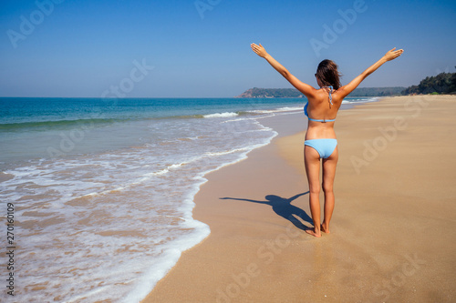 Young female imodel n a stylish blue bikini swimsuit enjoying sunny day on tropical beach paradise hotel resort.freedom and independence woman concept.copespase foam wave spf sunscreen photo