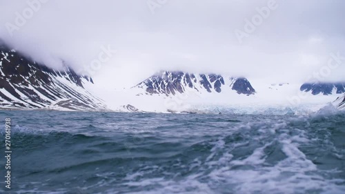 Sailing across a glacier and snow capped mountains on a yacht in the Arctic.