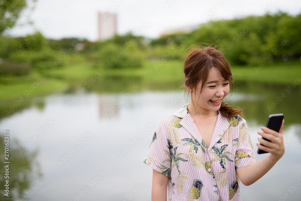 Young beautiful Asian tourist woman relaxing at the park