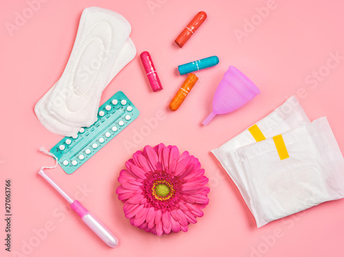 Tableau sur toile Sanitary napkins, tampons, contraceptive pills, menstrual cup and gerbera flower on pink background