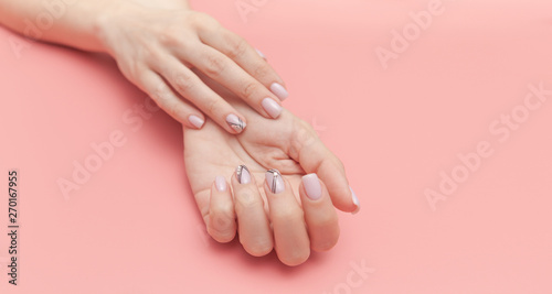 Beautiful young woman's hand with perfect manicure on pink background. Flat lay style.