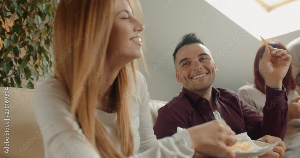 Friends eating pizza and chips on the sofa at home. Shot in slow motion Friends eating pizza and chips on the sofa at home. Shot in slow motion