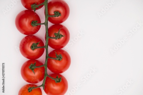 Cherry tomatoes on branch isolated on white background. Top view. © Natasa